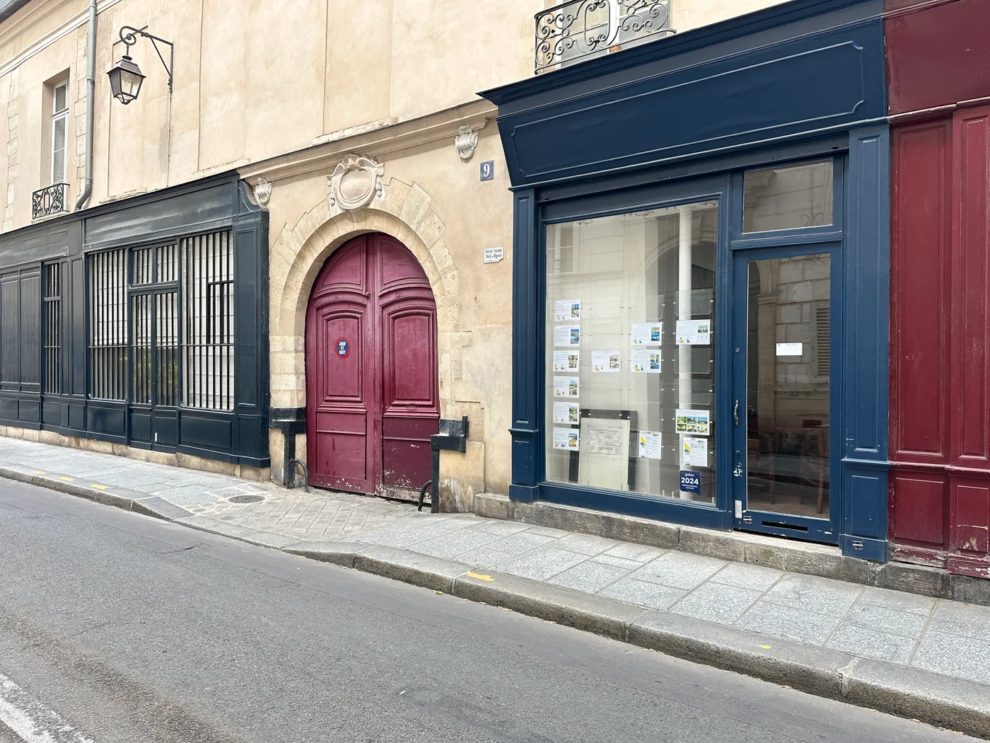 Façade sur rue avec vitrine bleue et porte cochère rouge — Paris, 75004.