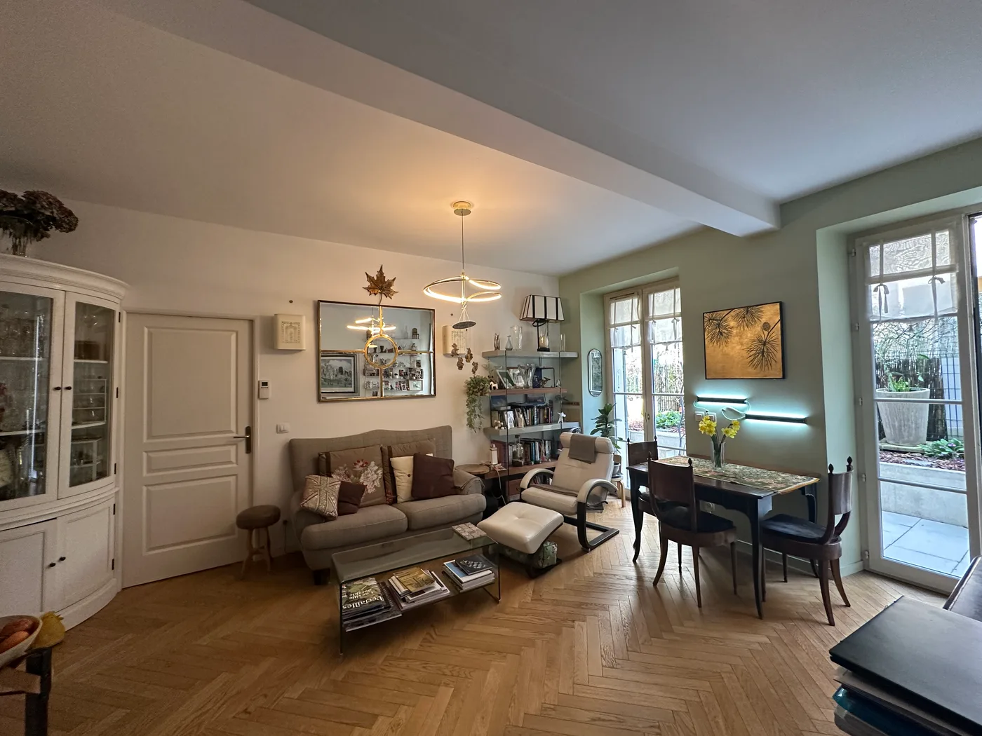 Séjour avec parquet en chevrons, coin repas et porte-fenêtre sur le balcon — Versailles, 78.