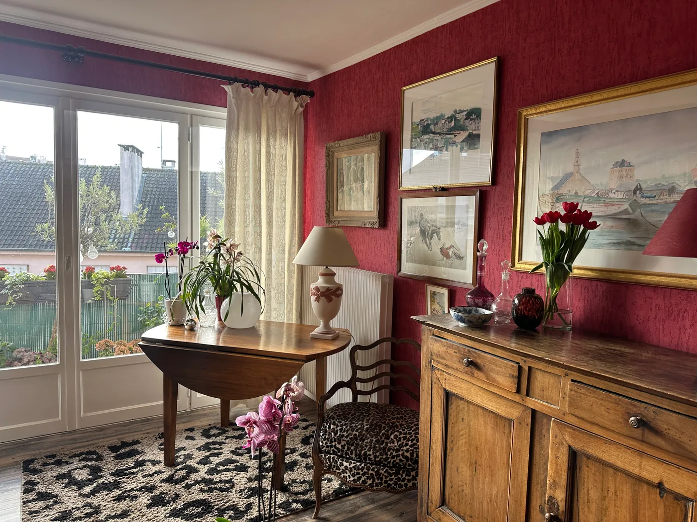 Coin repas avec mur rouge et porte-fenêtre donnant sur le balcon — Maurepas, 78.