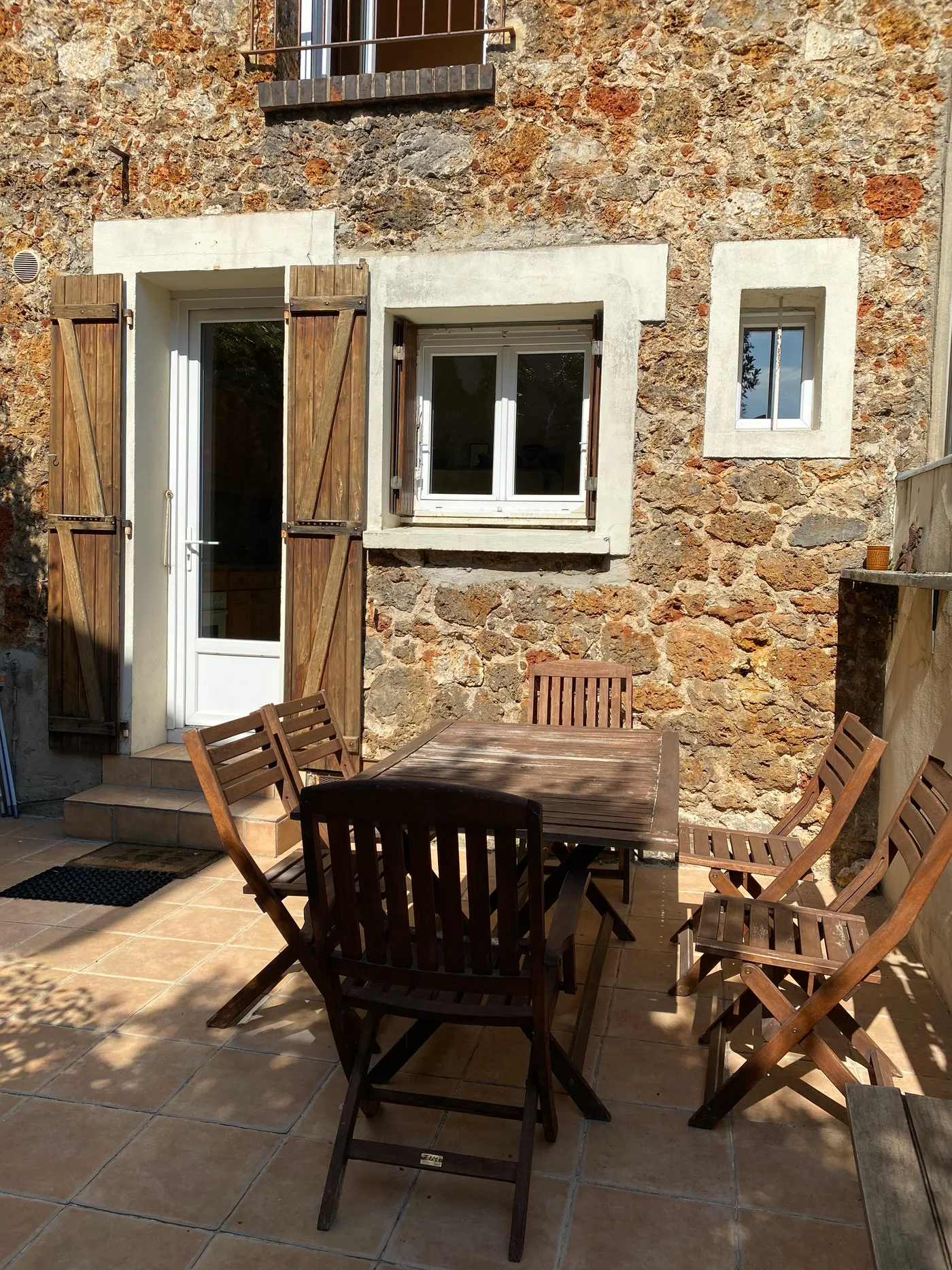 Terrasse avec table et chaises devant une façade en pierre — Cachan,94.